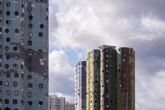 Cylindrical towers shape a residential urban architecture skyline in Paris, France, where a patterned facade rises beneath layered clouds and soft light