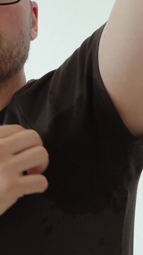 Close-up of a dark sweat stain under a man&rsquo;s armpit, showing excessive sweating, body odor concerns, hygiene issues, and antiperspirant need.