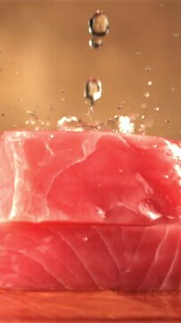 Super slow motion on raw tuna steaks drops water. On a brown background. Filmed on a high-speed camera at 1000 fps.High quality FullHD footage