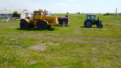 Obraz premium Yellow heavy articulated tractor and small blue tractor in a rural pasture