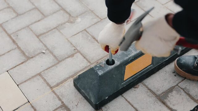 Worker securing rubber parking wheel stop on paving blocks close up