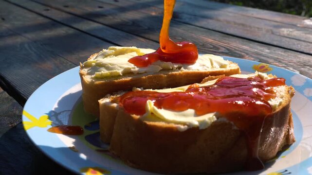 sandwich with butter spread with apricot jam outdoors in sunny warm weather