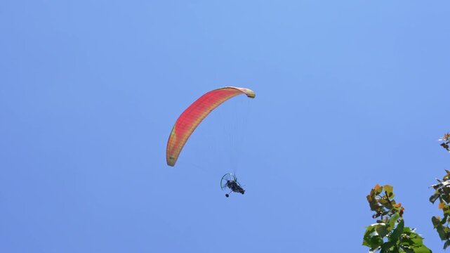 Paramotor (Powered Paraglider) with OrangeWing Flying in Clear Blue Sky