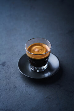 Coffee in glass cup on a dark stone background. Soft focus. Close up. Copy space.