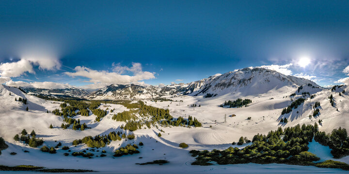 Aerial view of the snow-covered mountains and pine forests of UNESCO Biosphare Entlebuch under a bright sun in Soerenberg, Luzern, Switzerland.