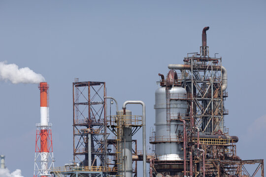 Industrial refinery complex with distillation columns linked to steel piping network in petrochemical processing facility, illustrating energy production and ecological impact in industrial landscape.