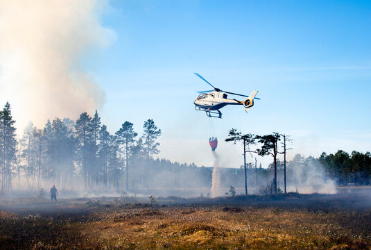 Helicopter pouring water with bucket on land while flying in sky