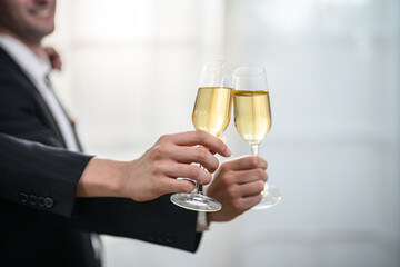 Two people in suits clinking champagne glasses in celebration © FotoArtist