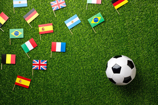 Soccer ball on a football field with international flags. Concept of global football world cup, international teams, competition and world championship. Top view, flat lay.