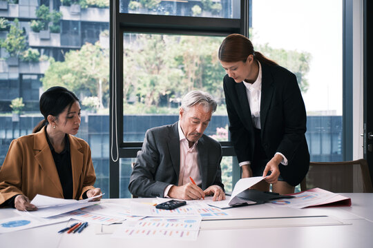 White senior male CEO seriously works in boardroom, signs business contract documents from female secretary, corporate financial report, and investment project, and executive leadership president.