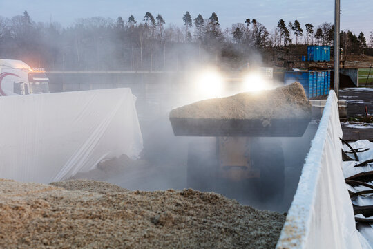 Backhoe picking up agricultural waste while working in farm