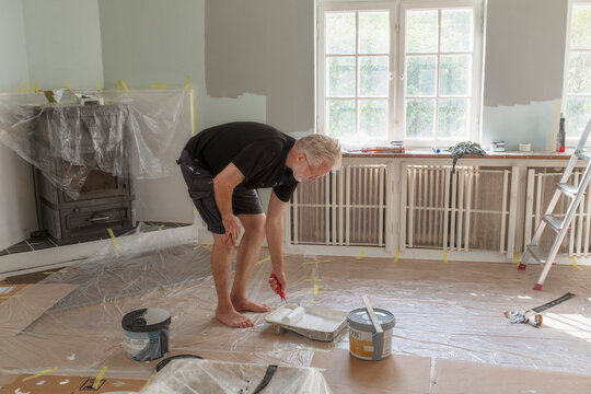 Full length of senior man dipping roller in paint