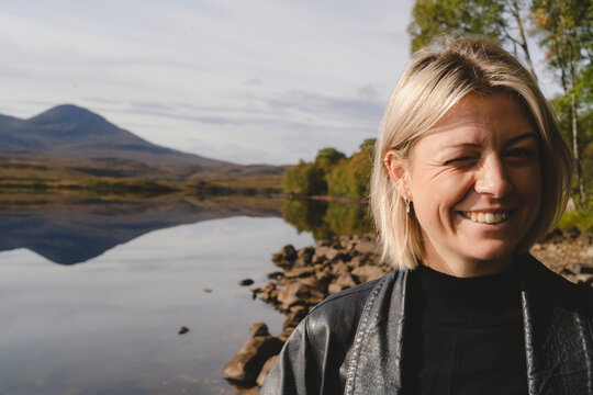 Portrait of woman with blond hair winking while hiking in forest