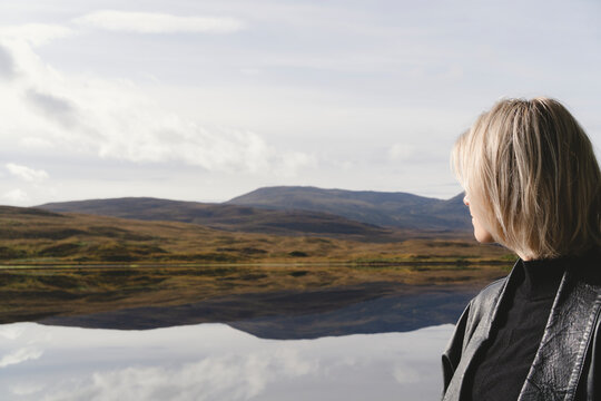 Woman with blond hair looking at mountains while hiking in forest