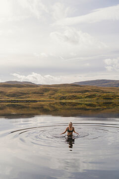 Carefree woman swimming in lake against sky