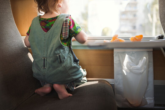 Rear view of boy looking out of window while kneeling on train seat