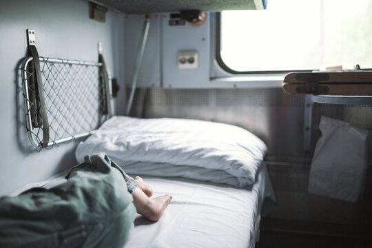 Low section of boy sleeping on bed in train cabin