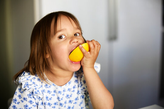 Portrait of girl eating fruit at home