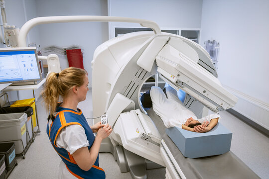 Female medical professional monitoring patient during X-ray scan at clinic