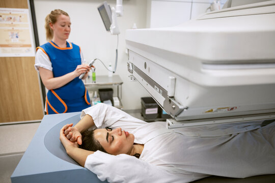 Woman with eyes closed undergoing through medical X-ray at clinic