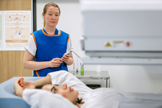 Female healthcare professional monitoring patient undergoing MRI scan examination