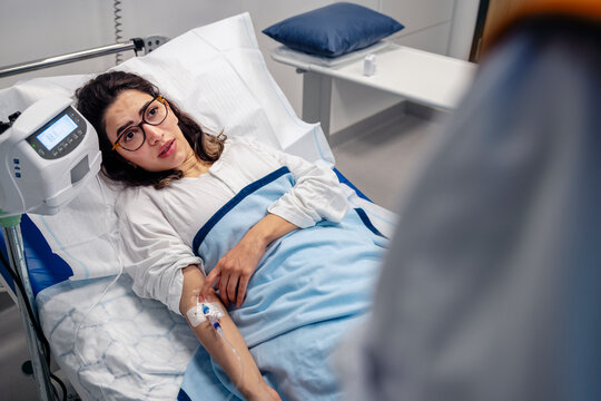 High angle view of patient talking with doctor while lying on bed in hospital