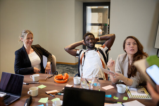 Group of male and female employees discussing strategies while sitting casually in office meeting room