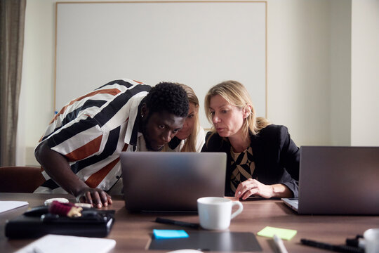 Focused male and female entrepreneurs examining data over laptop at office