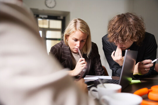 Thoughtful male and female entrepreneurs examining data at office