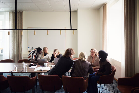 Male and female business professionals sharing marketing ideas while sitting in office meeting room