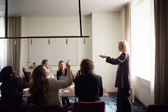 Side view of female entrepreneur interacting with colleagues in office meeting