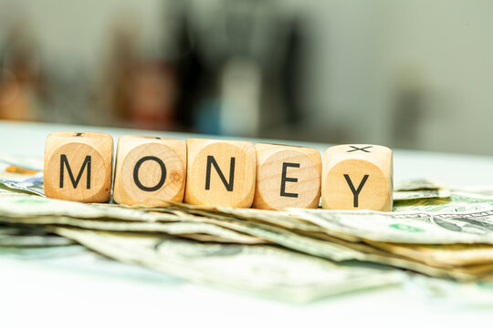 Conceptual image showing wooden letter blocks spelling out the word money on a pile of US dollar bil