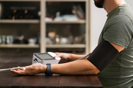 Cuff wrapped around arm of man for checking blood pressure at home