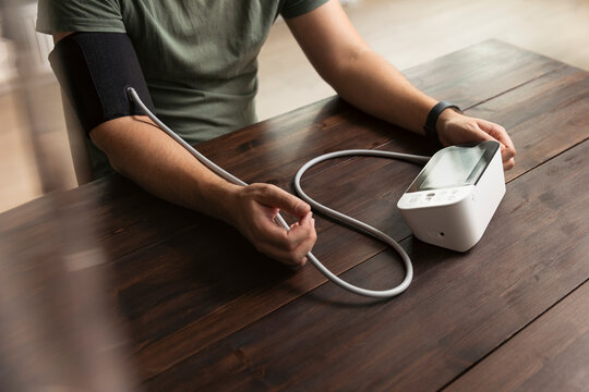 Man checking his blood pressure while sitting at table in home