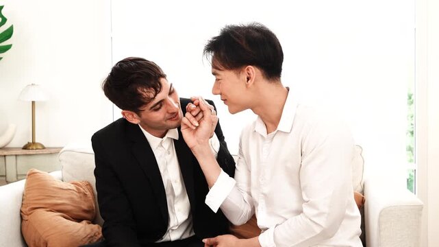 Pride and LGBTQ concept: LGBT couple, a gay man kissing a man, both romantically exchanging rings on a bed at home.

   

