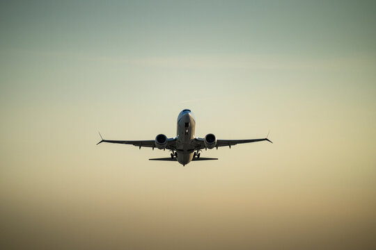Passenger plane flying high in sky at sunset