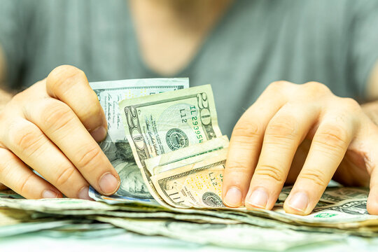 Close up shot of hands carefully counting a stack of US dollars bills