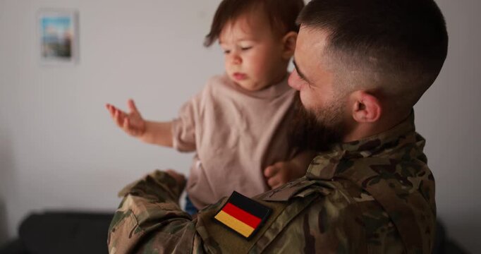 Male german soldier in military uniform hugs his little son at home - Emotional military happy homecoming concept
