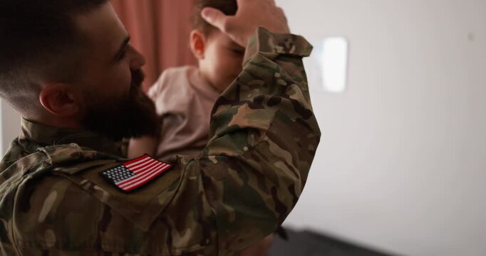 American soldier man in military uniform having tender moment with little son at home - Emotional and happy military homecoming concept - Focus on the arm 
