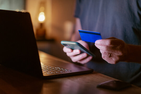 Midsection of man doing online payment through smart phone and credit card at home