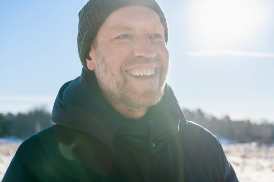 Headshot of happy male explorer wearing knit hat looking away