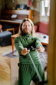 Active man performing kneeling cable rows on yoga mat at home