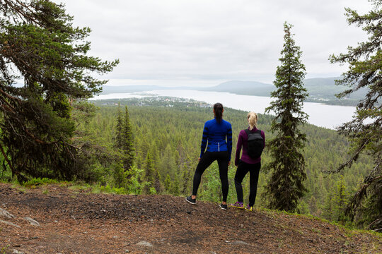 Rear view of female hikers looking at river while standing on cliff