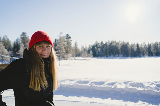 Portrait of smiling long haired woman wearing knit hat standing against clear sky