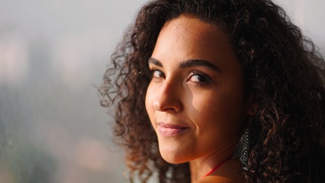 Young woman with beautiful curly hair smiling, looking at camera