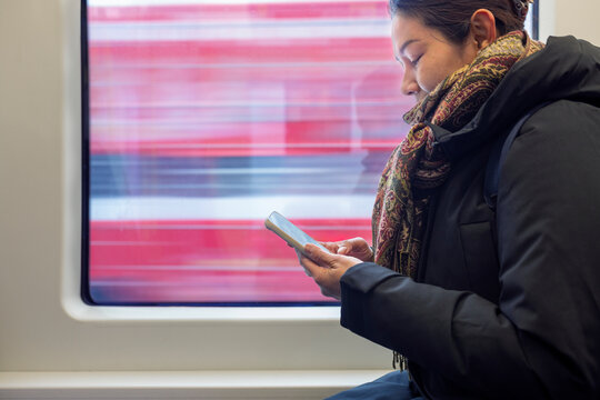 Side view of woman using smart phone while sitting in moving train