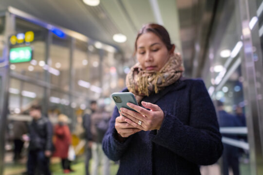 Low angle view of woman using smart phone at railway station