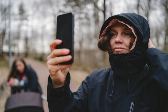 Smiling woman wearing zipper photographing with smart phone during weekend travel