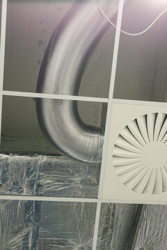Close view of corrugated metal ductwork and white air vent diffuser
