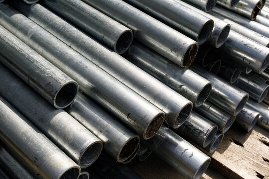 Close up view of stacked industrial metal pipes, ready for building projects.